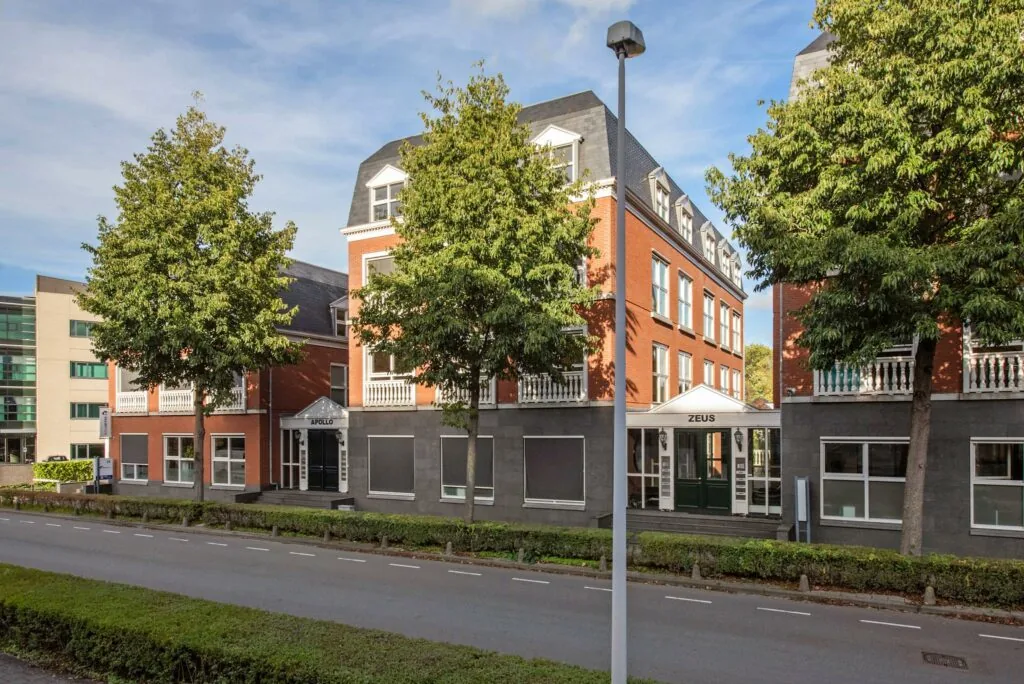 Kantoorgebouwen Apollo en Zeus aan de Laan van Vredenoord, omgeven door bomen en gelegen aan een rustige weg.